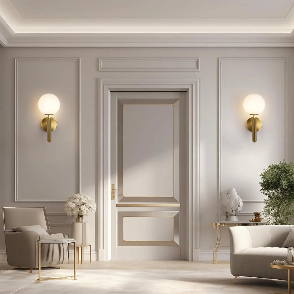 Deux appliques minimalistes dorées à globe de verre blanc, de part et d'autre d'une porte